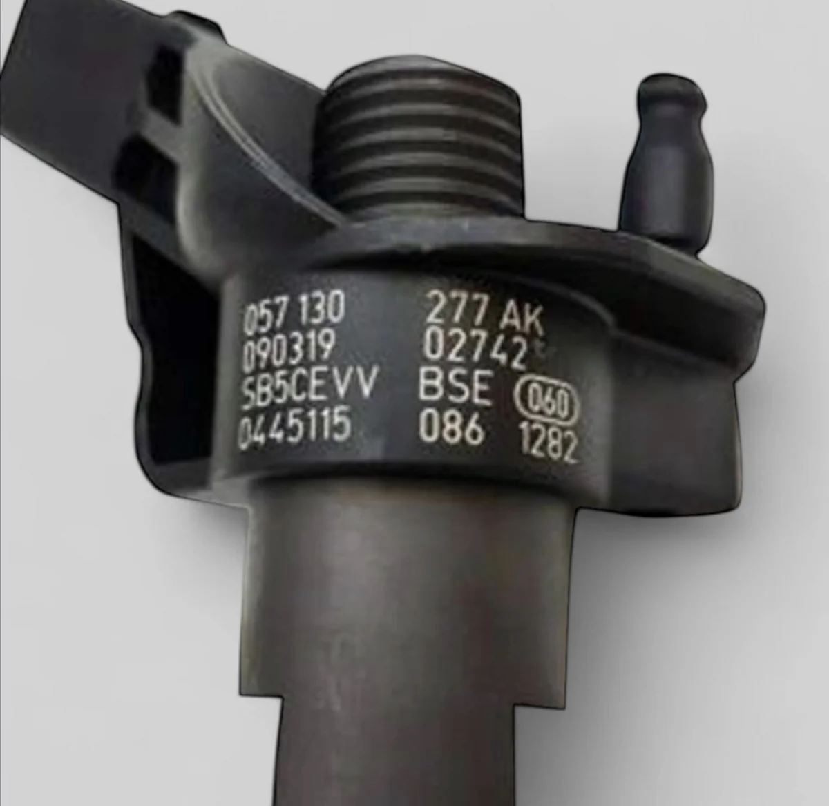 Close-up of Audi OE 057 130 277 AK and Bosch 0445115 086 part number markings on 0445115085 family injector